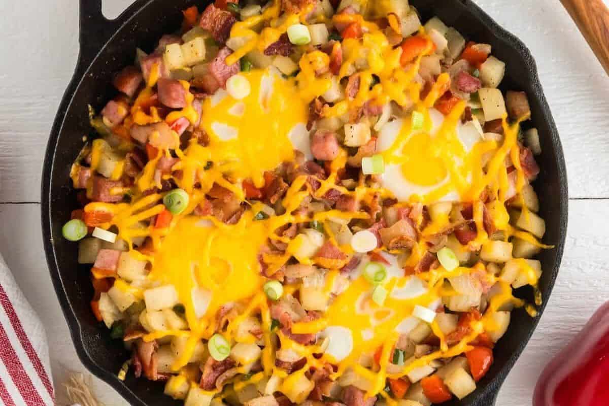 This skillet features diced potatoes, ham, red bell peppers, and melted cheese topped with two eggs—perfect for adding to your collection of Easter brunch recipes.