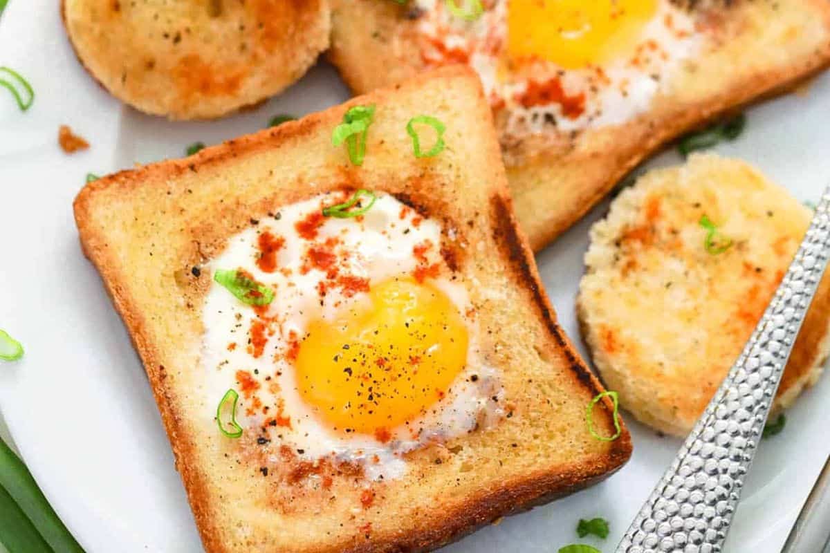 Toasted bread with a cooked egg in the center, garnished with green herbs and spices, served on a white plate—a delightful addition to your Easter brunch recipes.