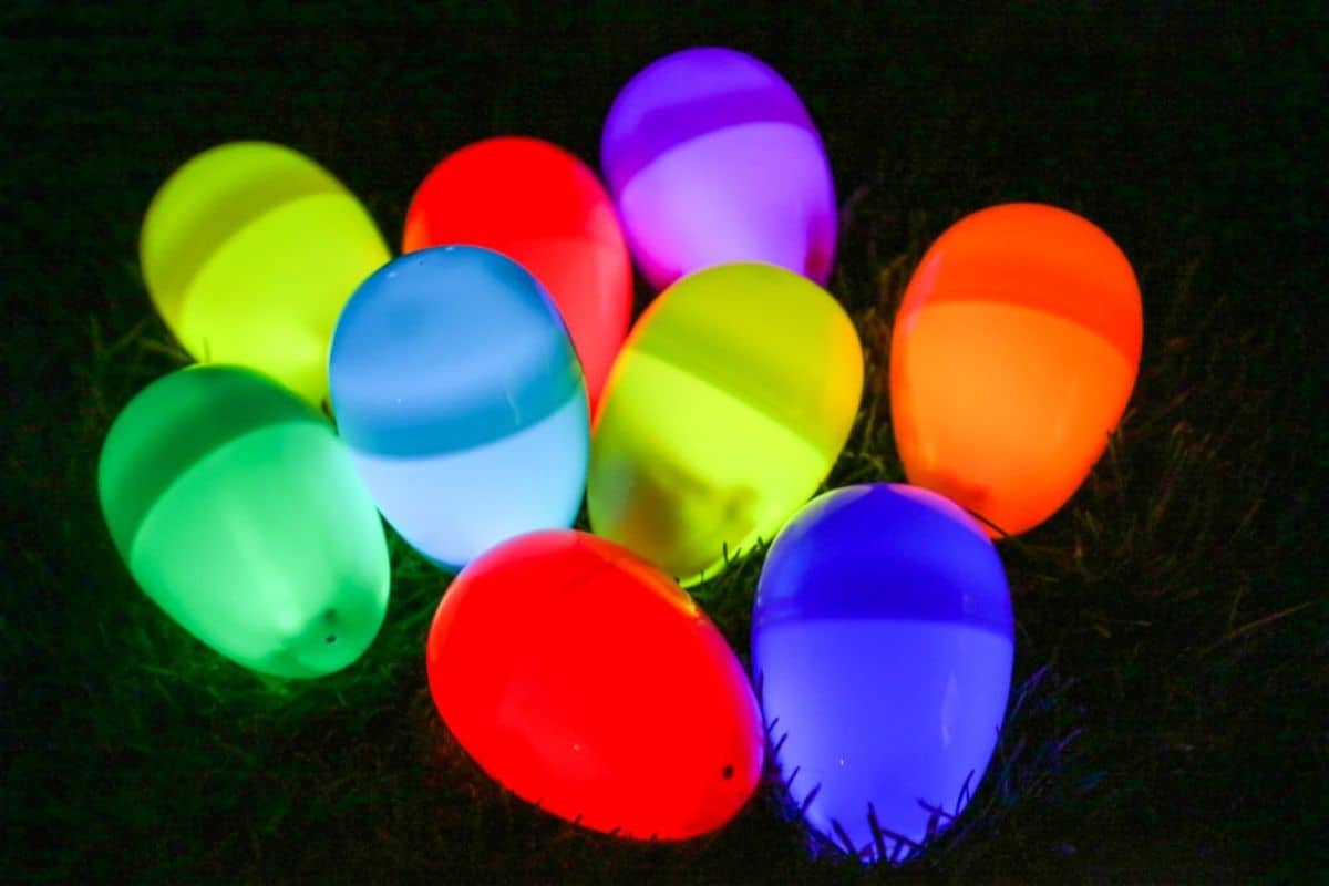 In the dark, glowing multicolored plastic eggs are creatively arranged on grass, adding a touch of Easter magic.