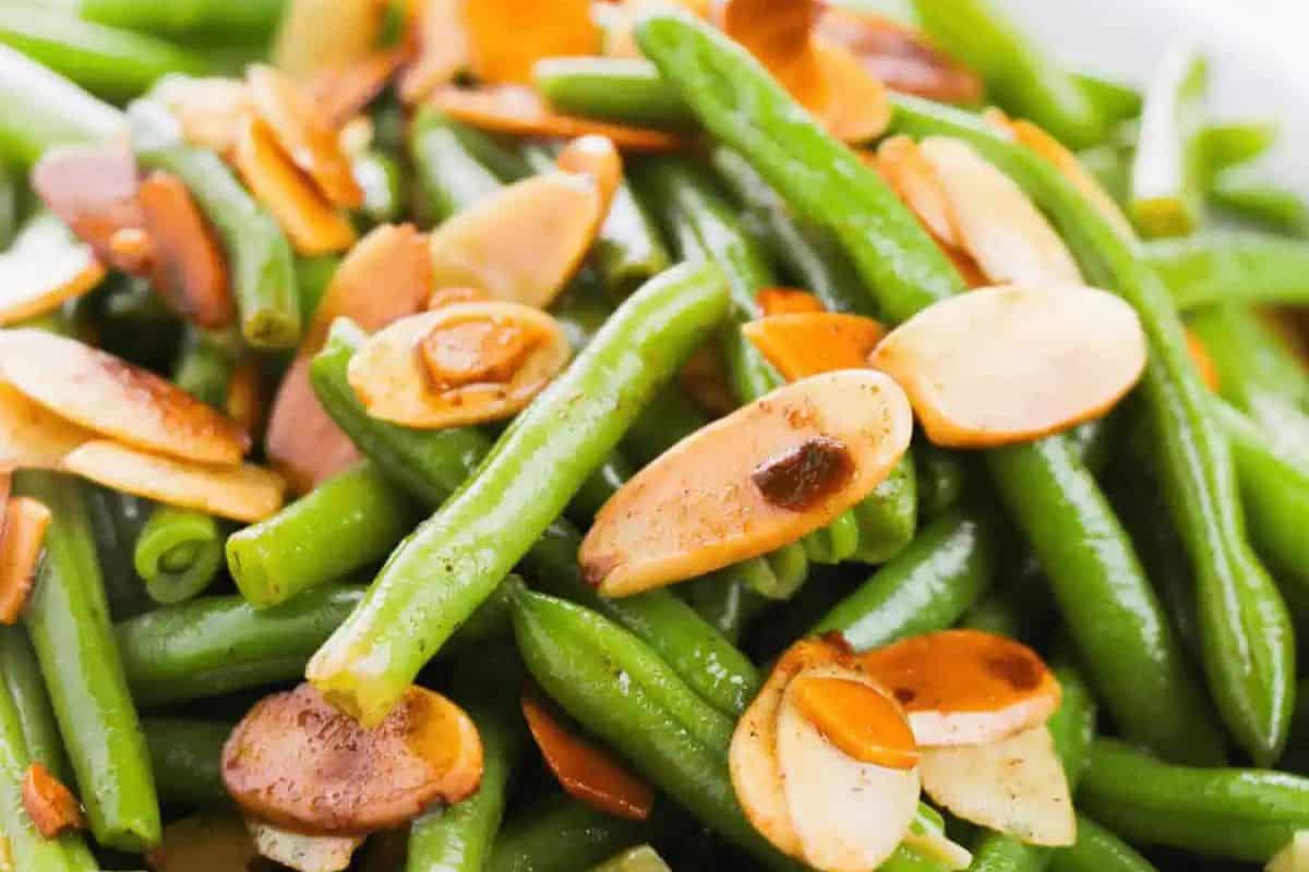 A close-up of cooked green beans topped with sliced, toasted almonds—a delicious recipe perfect for a baby shower.