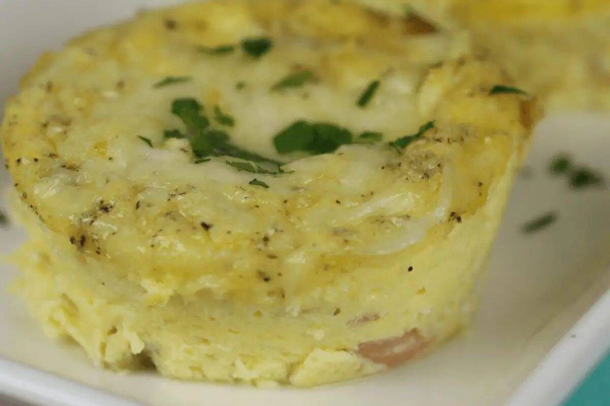 Close-up of a savory egg muffin, an Easter brunch favorite, topped with fresh herbs on a white plate.