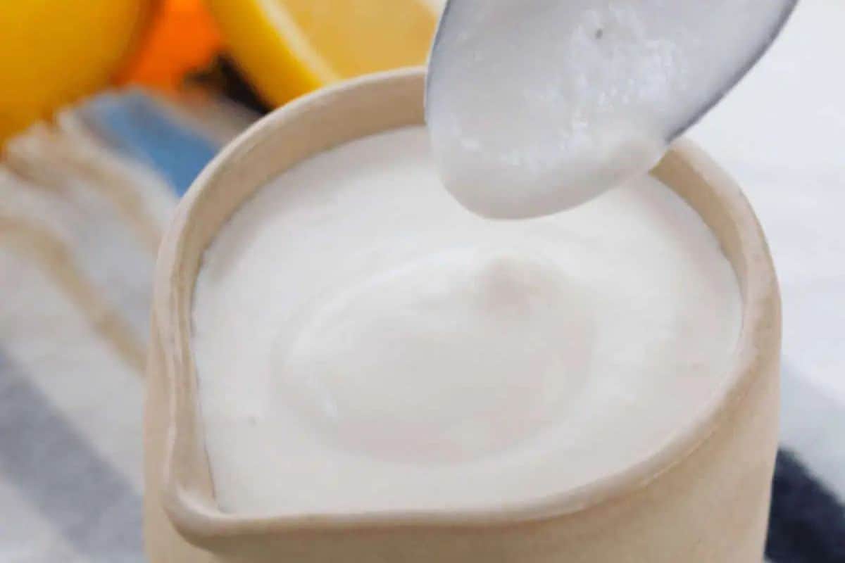 Lemon tahini dressing in a ceramic bowl, with a spoon scooping out a portion, showing its creamy white texture.