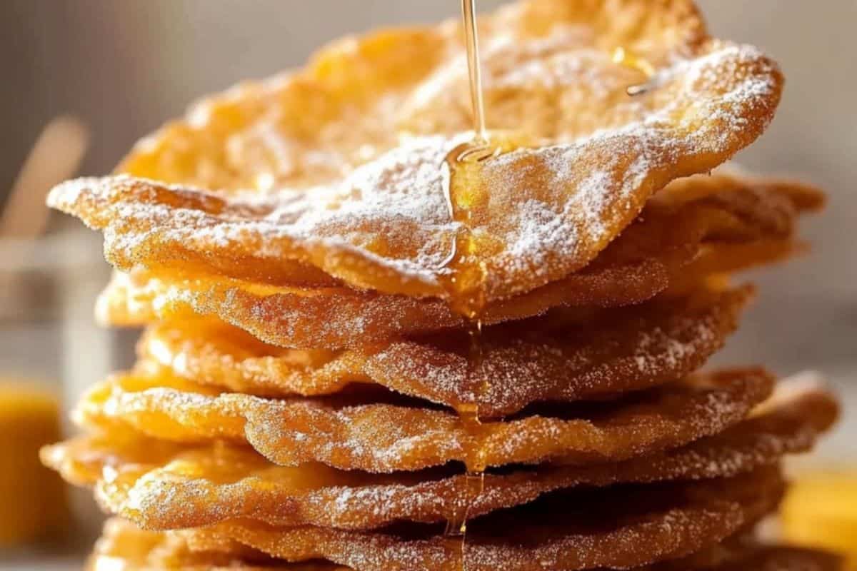 A stack of honey-drizzled, sugar-dusted buñuelos sits enticingly on a table, perfect for adding a sweet touch to any fiesta.