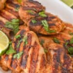 The finished meal topped with are garnished with chopped cilantro on a white plate and accompanied by fresh lime wedges.