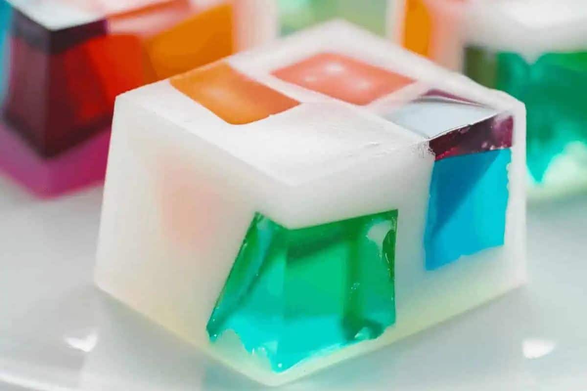 Close-up of a festive white dessert block embedded with colorful gelatin cubes, perfect for a Cinco de Mayo fiesta, on a white plate.