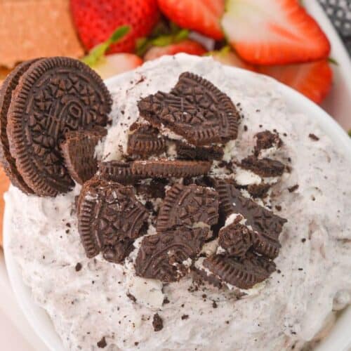 A bowl of luscious Oreo Dip, crowned with crushed chocolate sandwich cookies, sits invitingly among juicy strawberries and crisp graham crackers.