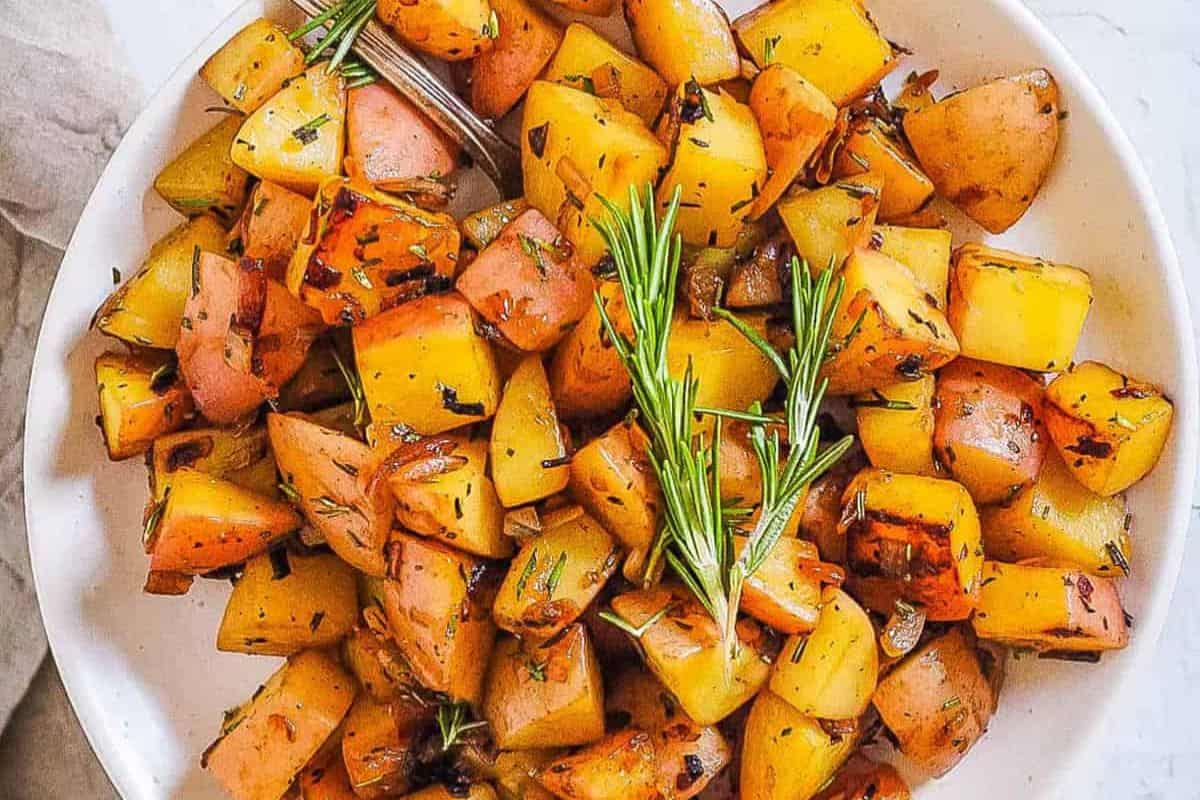 A bowl of cubed roasted potatoes garnished with rosemary sprigs, perfect for Easter brunch recipes.