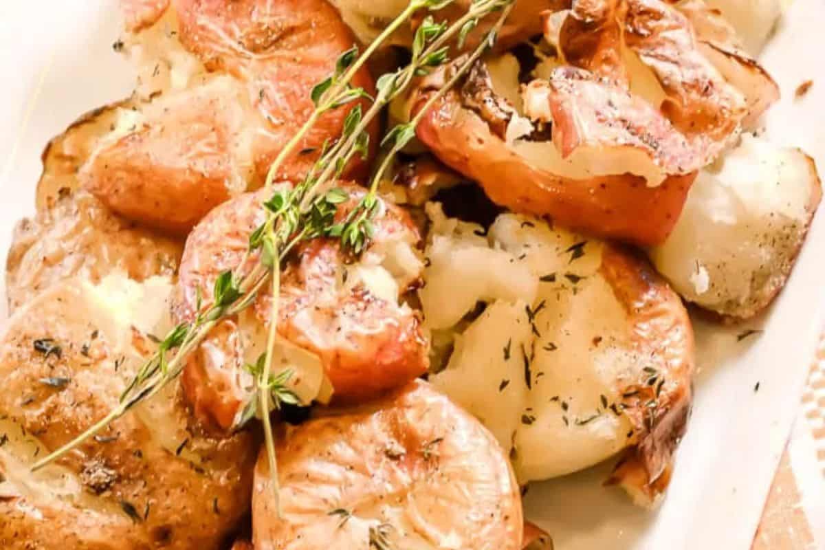 Close-up of roasted smashed potatoes garnished with fresh thyme on a white plate, perfect for Easter side dishes that will have everyone coming back for seconds.