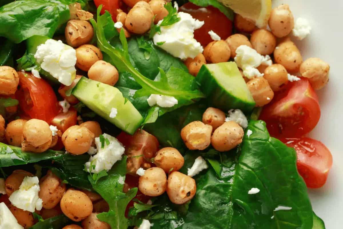 Discover one of the best spring salads with chickpeas, baby spinach, cucumber, cherry tomatoes, crumbled feta, and a lemon wedge. This delightful blend is a standout in seasonal recipes.