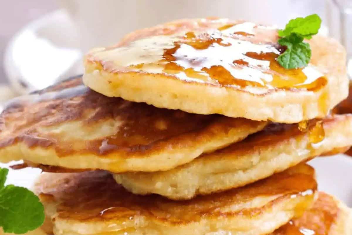 A stack of pancakes, perfect for Easter Brunch recipes, topped with melted butter and syrup, garnished with mint leaves.