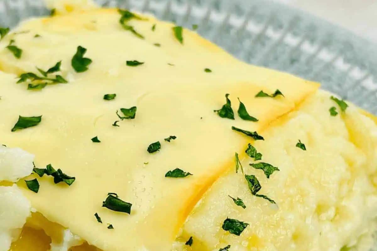 Close-up of a cheesy omelette sprinkled with chopped herbs on a plate, evoking cravings reminiscent of irresistible pierogi dishes.