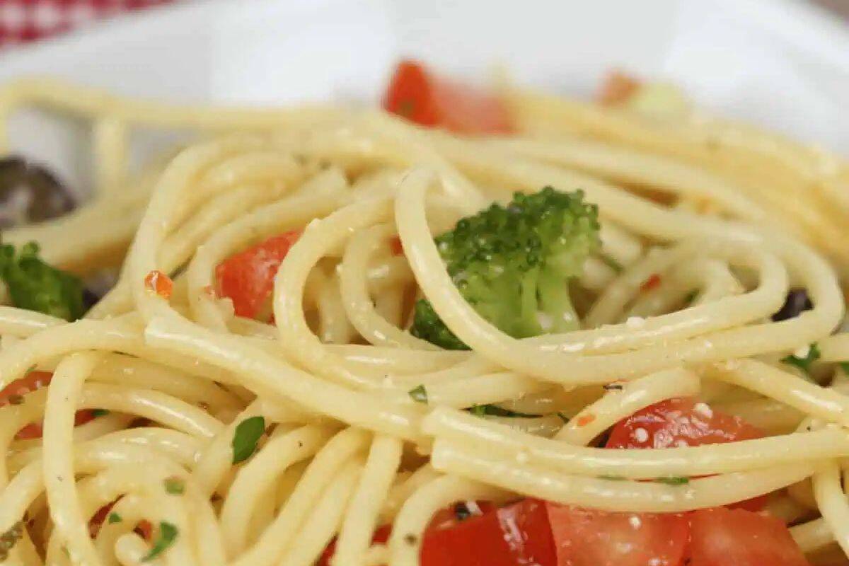A close-up of a Lent-friendly plate of spaghetti showcases vibrant broccoli, chopped tomatoes, and aromatic herbs—a delightful addition to your pasta recipes collection.