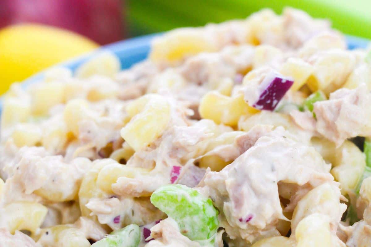 A hearty and creamy tuna pasta salad made with elbow macaroni, red onions, celery, and tuna, all coated in a tangy mayonnaise-based dressing. The dish is a great combination of protein and crunch.