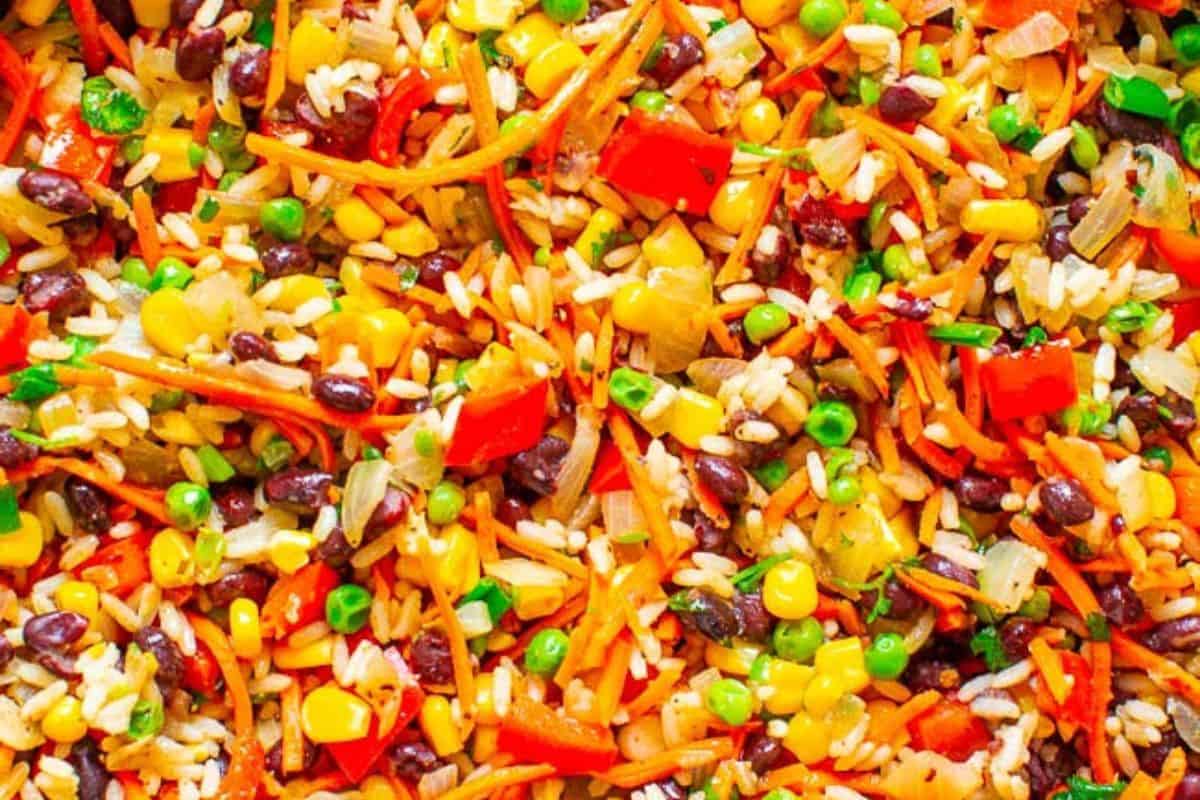 Colorful vegetable and rice medley with black beans, corn, peas, carrots, red bell peppers, onions, and green onions mixed together—a perfect option for meatless meals and delicious lent recipes.