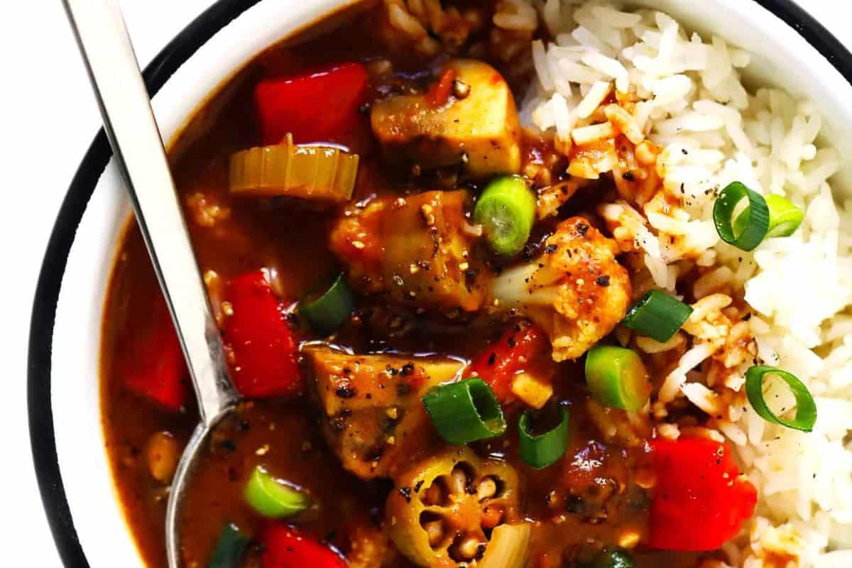 A bowl of gumbo with okra, celery, red bell pepper, steamed white rice, sliced green onions, and a spoon—perfect for meatless meals or Lent recipes when you crave comforting southern flavors.