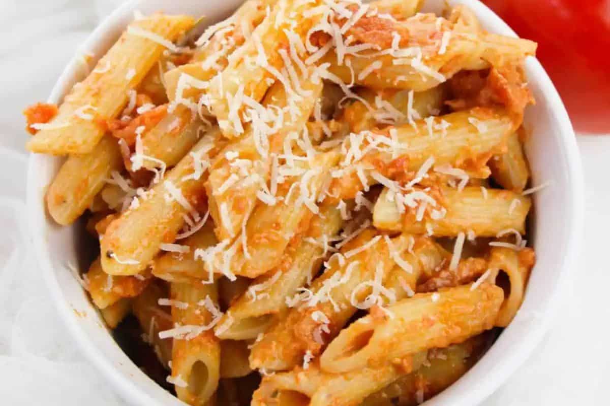 A white bowl filled with penne pasta in tomato sauce, topped with grated cheese—perfect for vegetarian Lent or other meatless recipes.