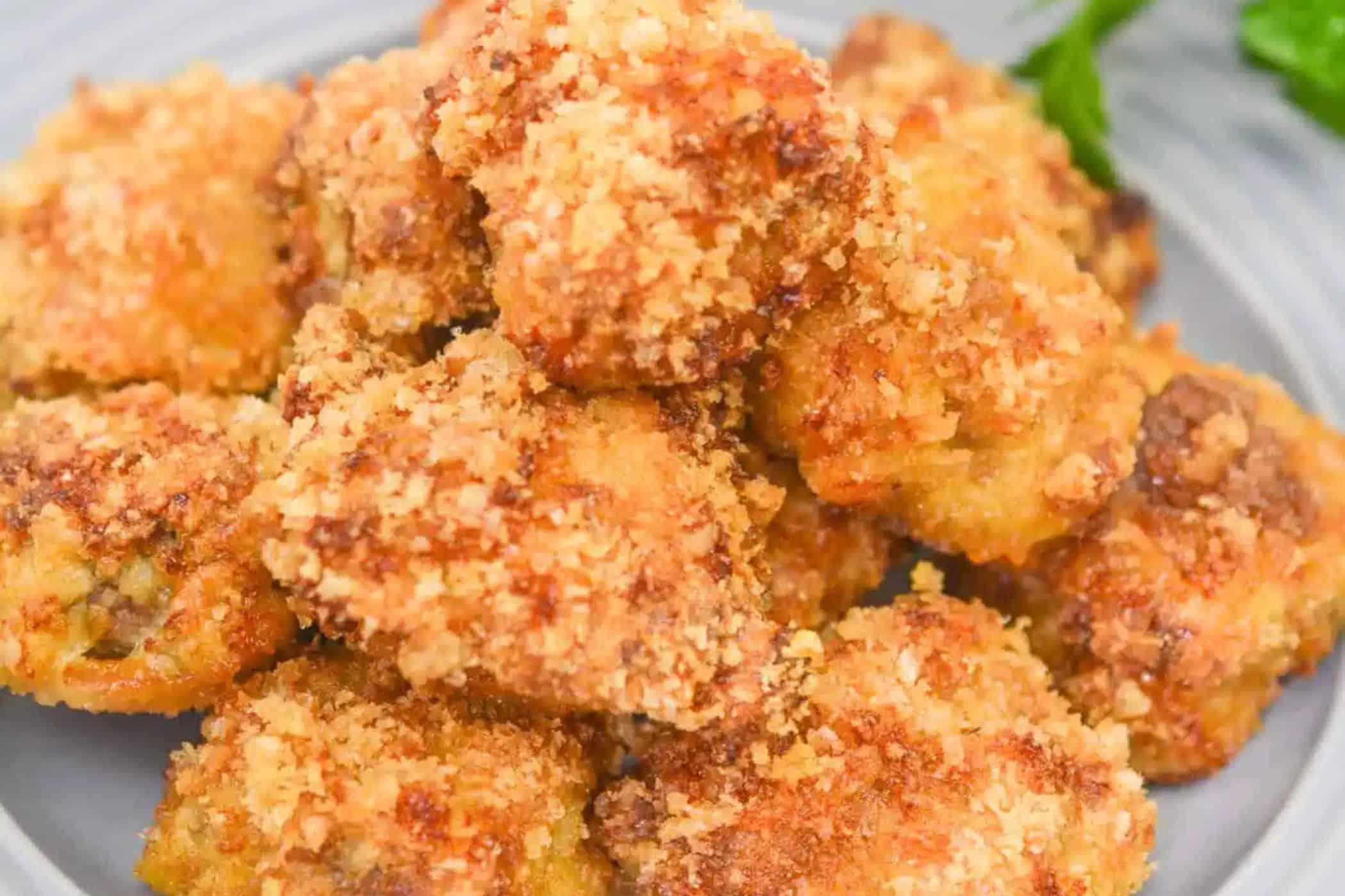 A close-up of a pile of golden-brown, breaded and air fried steak bites on a plate, garnished with a sprig of parsley—perfect inspiration for easy weeknight dinners or those who love simple cube steak recipes.