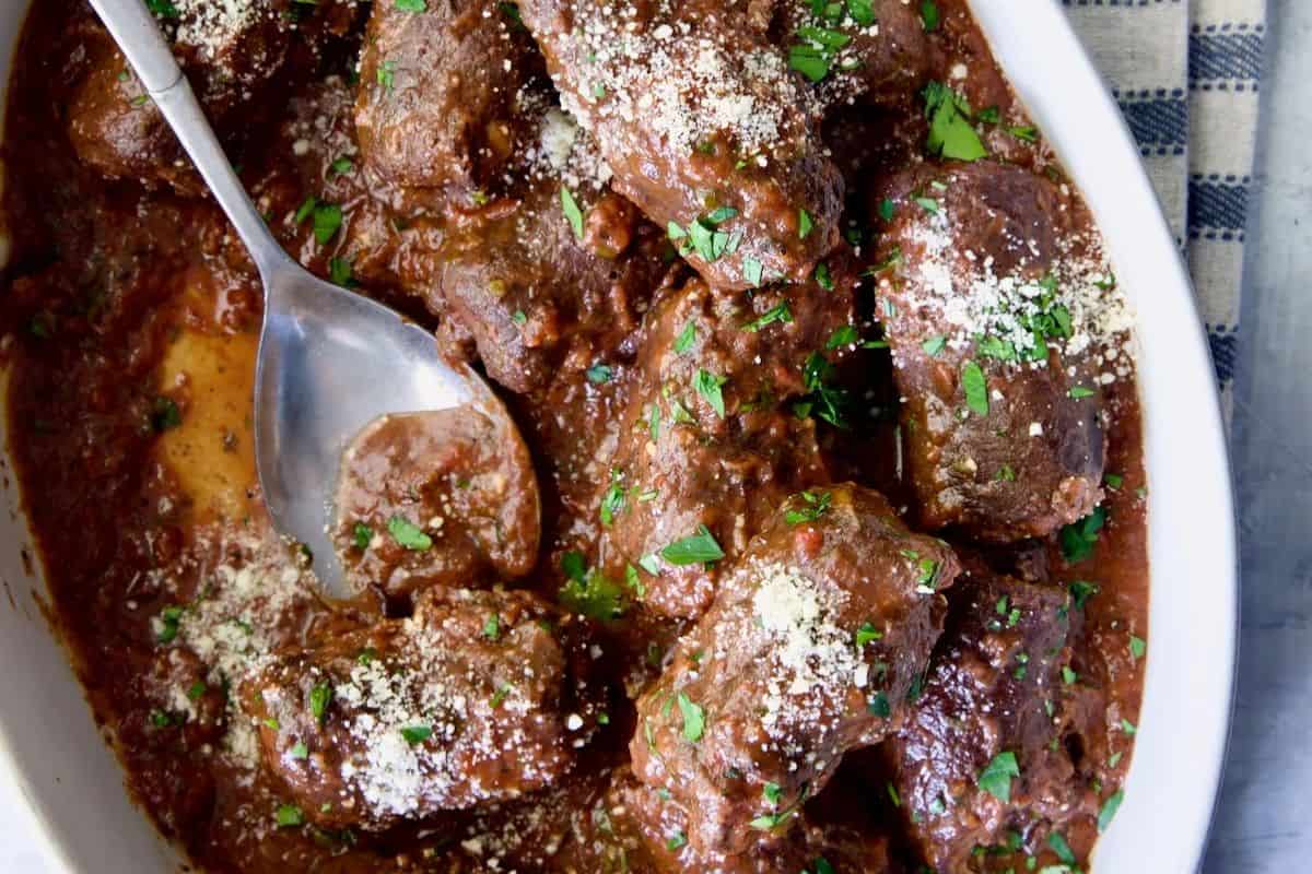 Beef Braciole, featuring rolled and stuffed beef braised in a tomato sauce with Parmesan cheese and parsley.