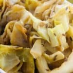 Close-up of braised cabbage pieces mixed with seasonings and sprinkled with caraway seeds in a white dish.
