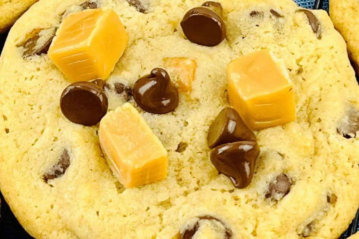 A close-up of a chocolate chip cookie topped with chocolate chips and caramel candy cubes, perfect for fans of indulgent desserts and easy caramel treats.