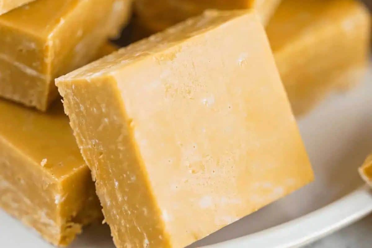 Close-up of several pieces of caramel fudge stacked on a white plate, perfect for fans of indulgent desserts and easy caramel recipes.