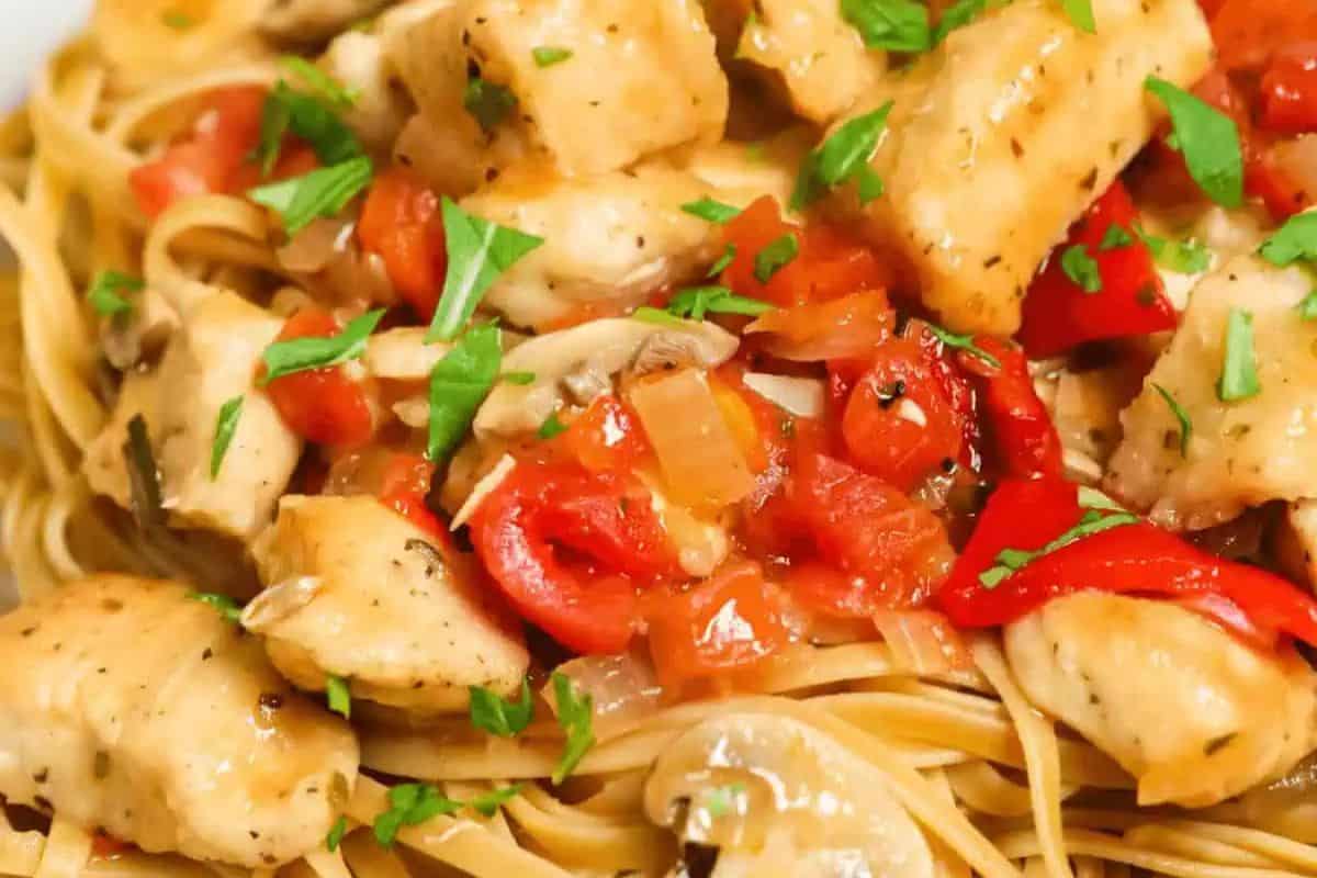 A delicious dinner plate of linguine topped with tender chicken pieces, diced tomatoes, earthy mushrooms, and a sprinkle of chopped parsley—perfect for two.