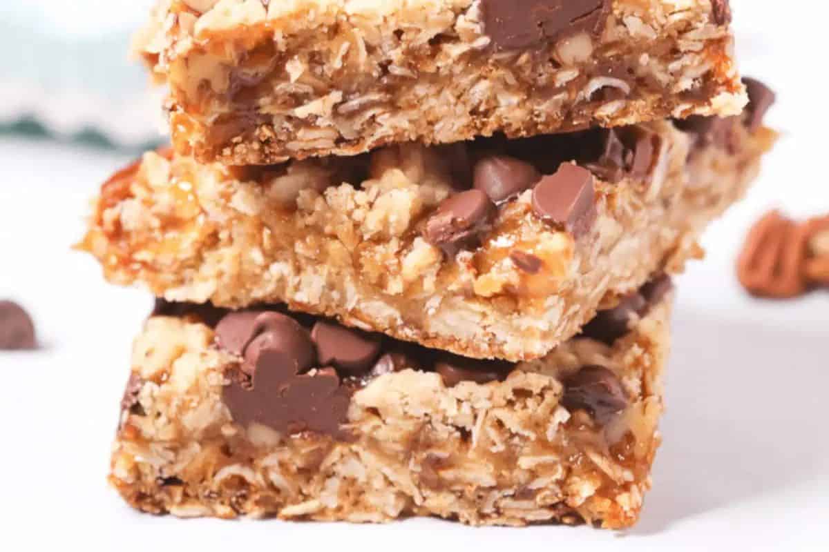 Three stacked homemade granola bars with oats, chocolate chips, and nuts, displayed on a white surface—perfect for fans of indulgent desserts or those seeking easy caramel recipes.