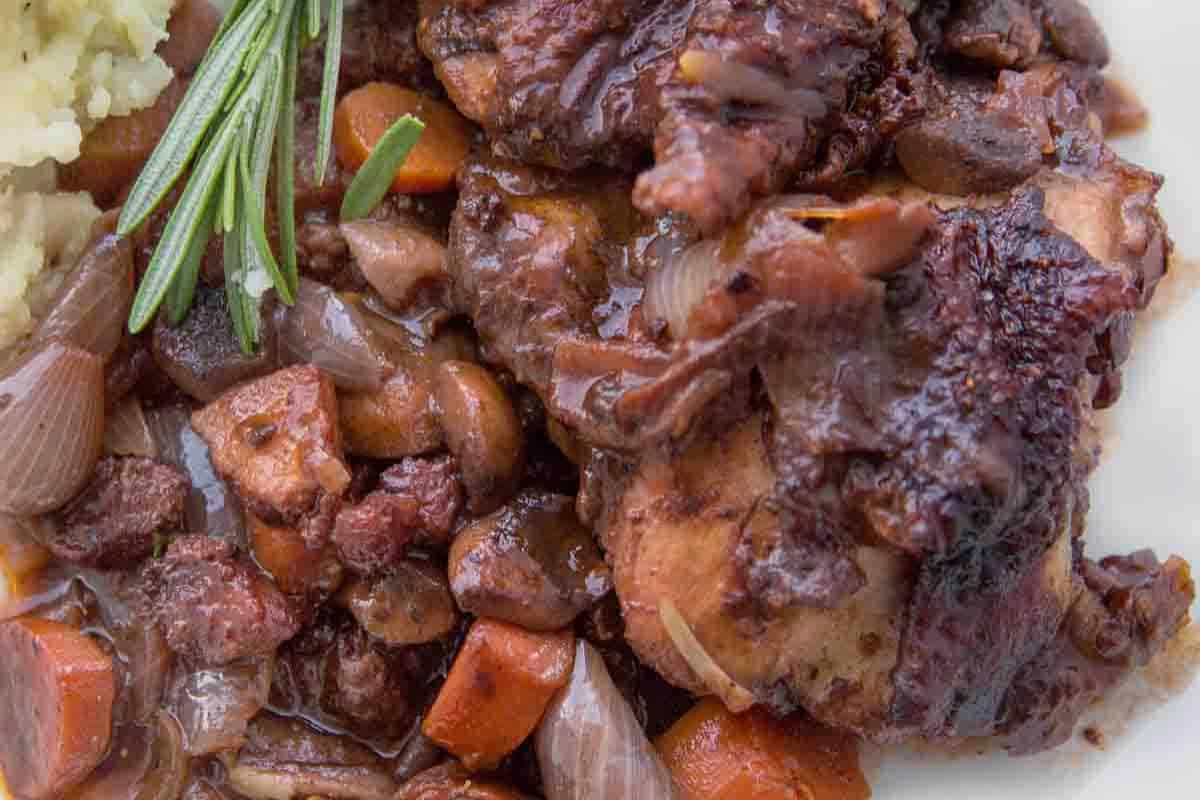 Classic Coq au Vin featuring chicken braised in red wine with mushrooms, onions, and carrots.
