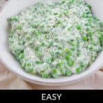 A bowl of classic creamed peas in a silky white sauce, sprinkled with black pepper, rests on a light surface. Text below reads, "Easy Grandma’s Creamed Peas.