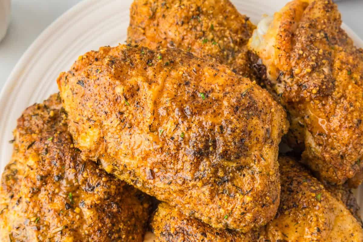 Close-up of several pieces of juicy chicken thighs, perfectly seasoned and baked, arranged on a white plate—ideal inspiration for your favorite chicken recipes.