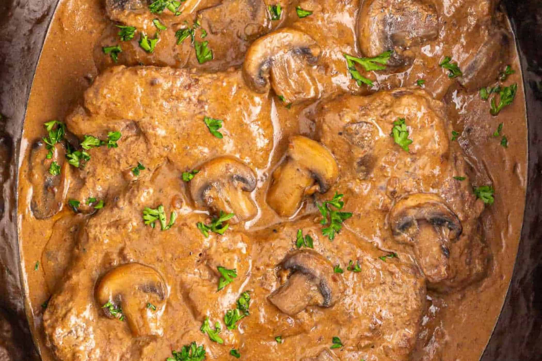Slices of beef covered in a creamy brown mushroom sauce, garnished with chopped parsley—a perfect addition to your cube steak recipes for busy weeknights.