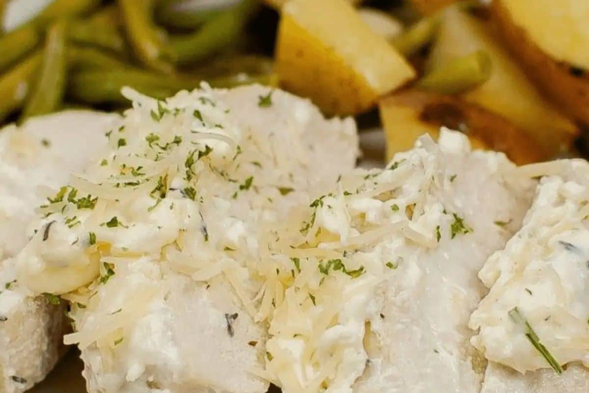 Savor a cozy dinner for two with a close-up of creamy chicken, elegantly topped with herbs and cheese. Paired perfectly with green beans and roasted potatoes, it's an easy dinner option that delights every palate.