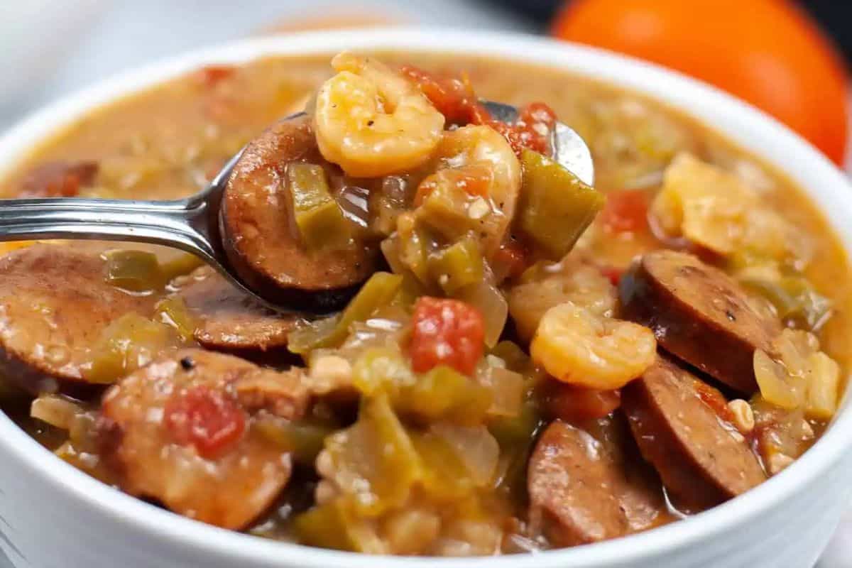 A close-up of a bowl of gumbo featuring sliced sausage, shrimp, chopped green peppers, tomatoes, and a rich broth—one of those game changing recipes that brings bold Southern flavor to your table.