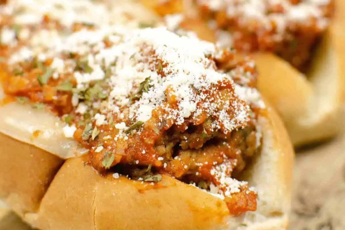 Close-up of a meatball sub sandwich topped with marinara sauce, melted cheese, herbs, and a sprinkle of grated Parmesan—this game changing meal is inspired by classic Instant Pot recipes for ultimate flavor and convenience.