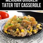 A serving of Chicken Tater Tot Casserole with corn, black beans, and crispy tater tots sits on a black plate, placed on a printed cloth.