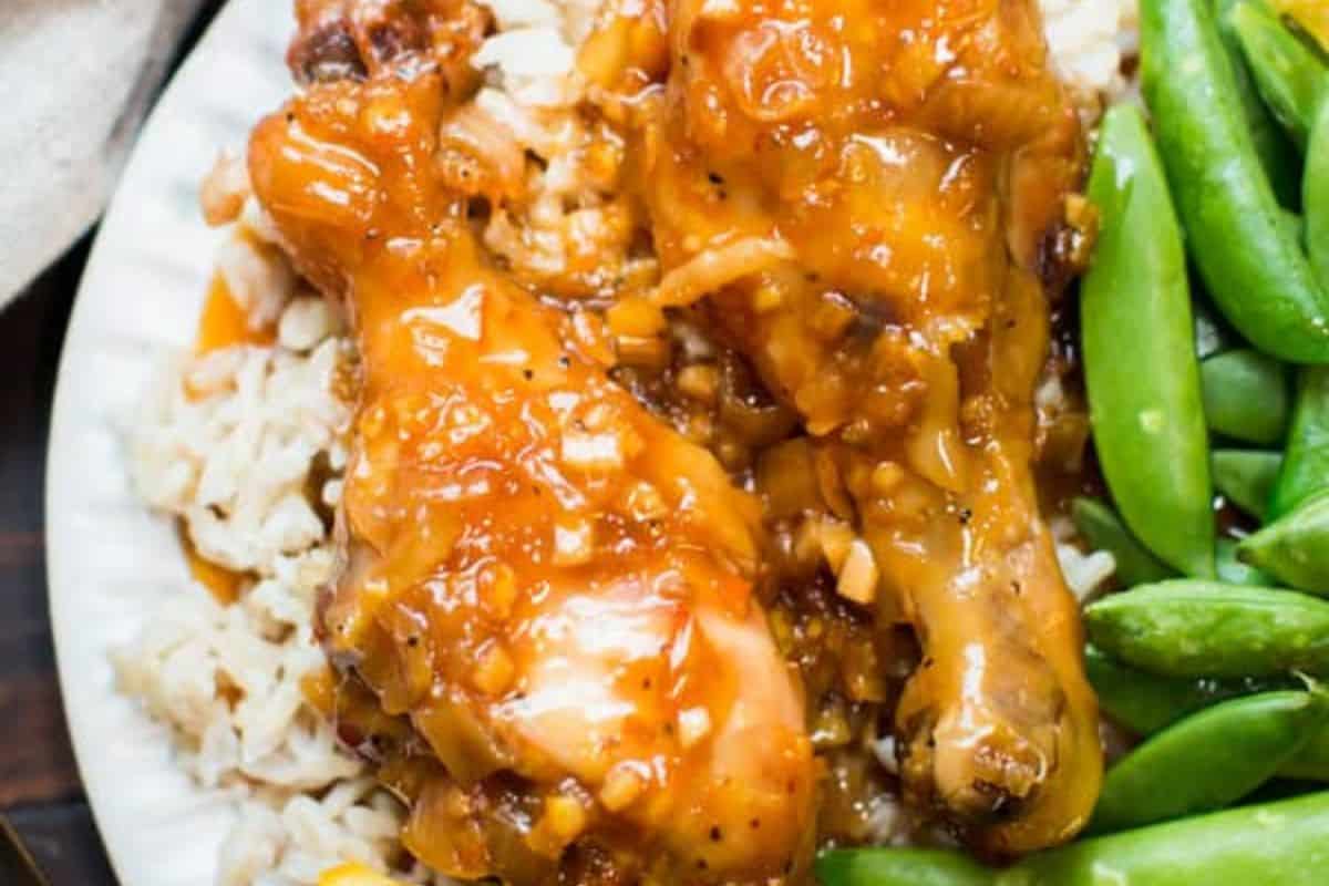 Two glazed chicken drumsticks on rice with a side of snap peas make this plate a must-try for fans of finger licking chicken and delicious chicken drumstick recipes.