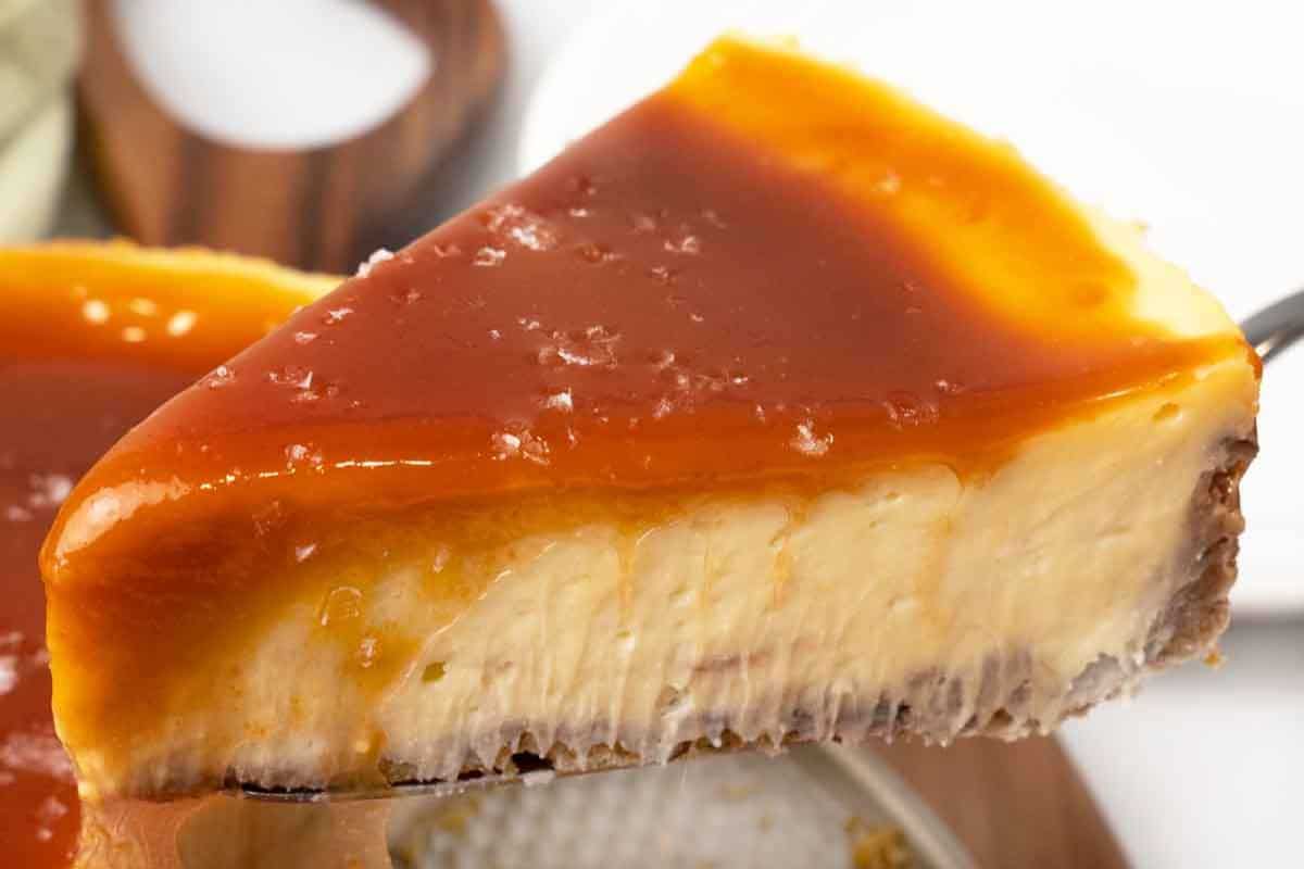 A close-up of a slice of cheesecake topped with a layer of caramel sauce, showing a creamy texture and a crumbly crust—perfect inspiration for those who love indulgent desserts.