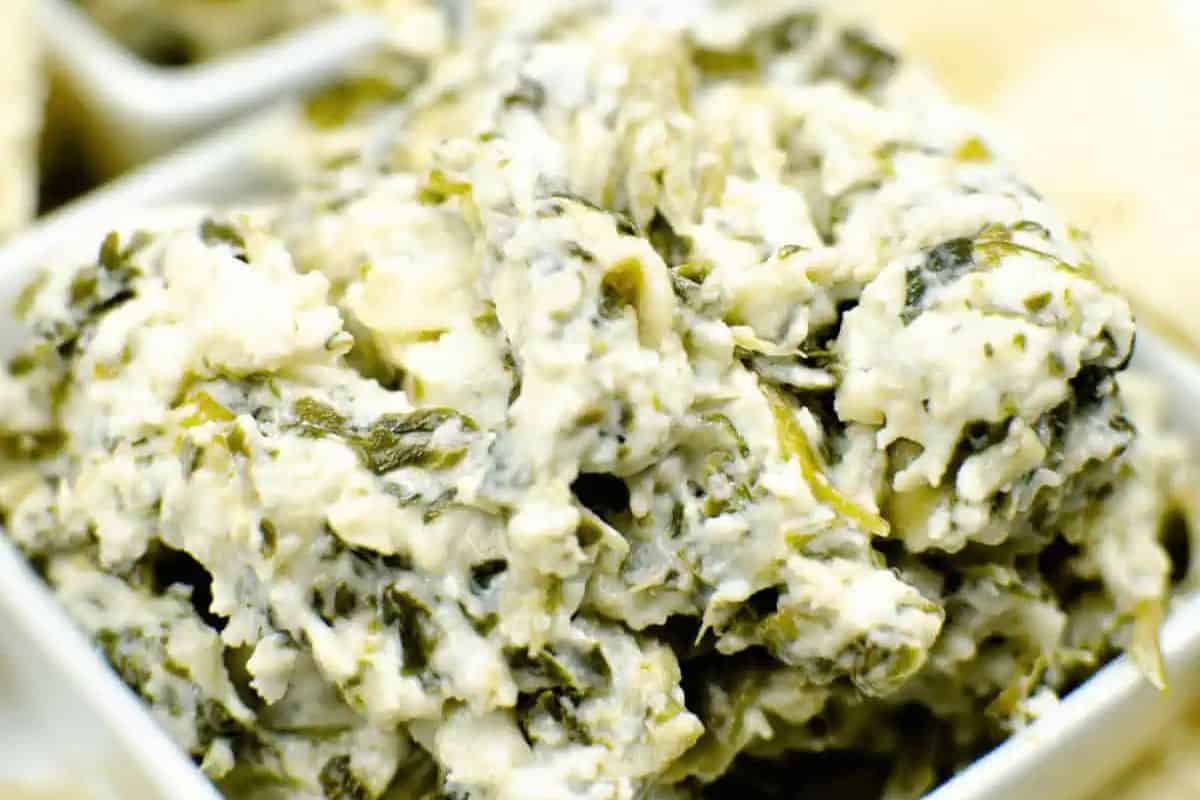 Close-up of creamy spinach and artichoke dip in a white dish—a game changing appetizer that you’ll want to repeat for every gathering.