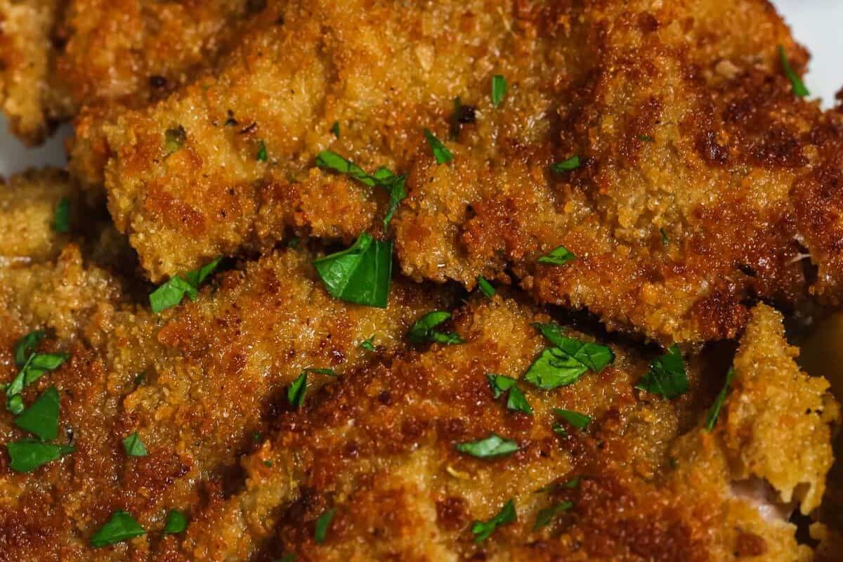 Close-up of crispy, golden-brown breaded veal pieces garnished with chopped parsley, perfect for a delicious dinner and inviting as a charming dinner for two.