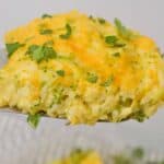 A close-up of a serving of velveeta broccoli rice casserole topped with chopped parsley.