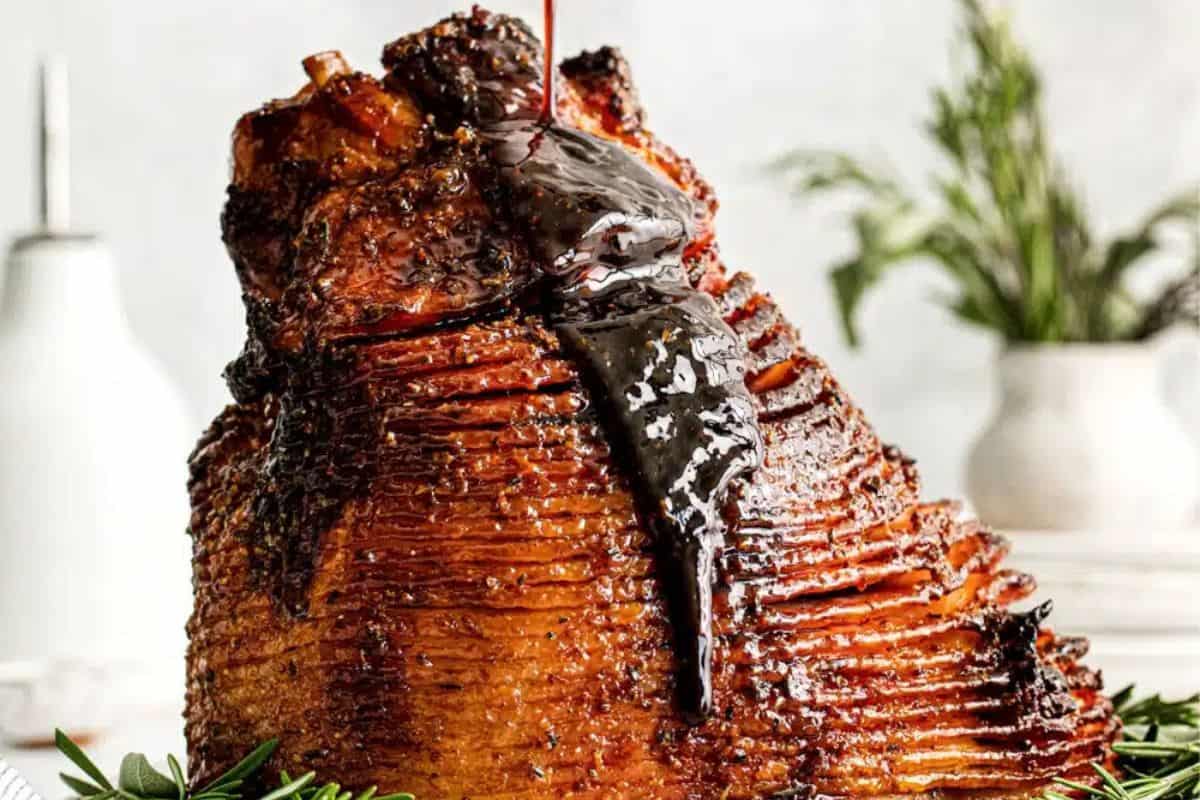 A showstopping spiral ham is drenched in a thick, glossy brown sugar glaze, cascading over the caramelized crust. The golden, candied edges promise bold, sweet-savory flavor in every bite. This image screams holiday indulgence and main dish glory.