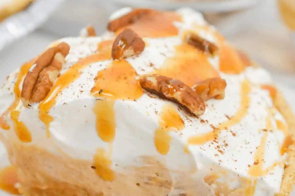 A close-up of a deliciously rich dessert, topped with whipped cream, pecans, and a decadent caramel drizzle—perfect for those exploring butterscotch recipes. Try today!.