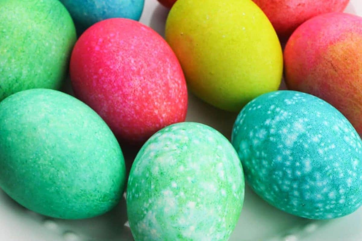 A plate of brightly colored, dyed Easter eggs in shades of green, blue, yellow, pink, and red—perfect inspiration for your next Easter Egg Decorating project.