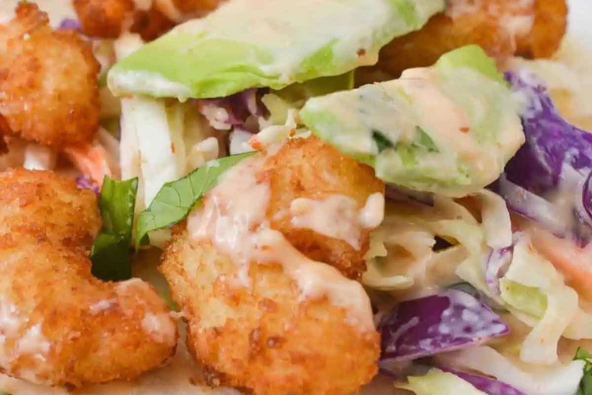 Close-up of breaded fried shrimp, sliced avocado, and coleslaw with a creamy sauce—a must try street food perfect for fans of flavorful street food recipes.