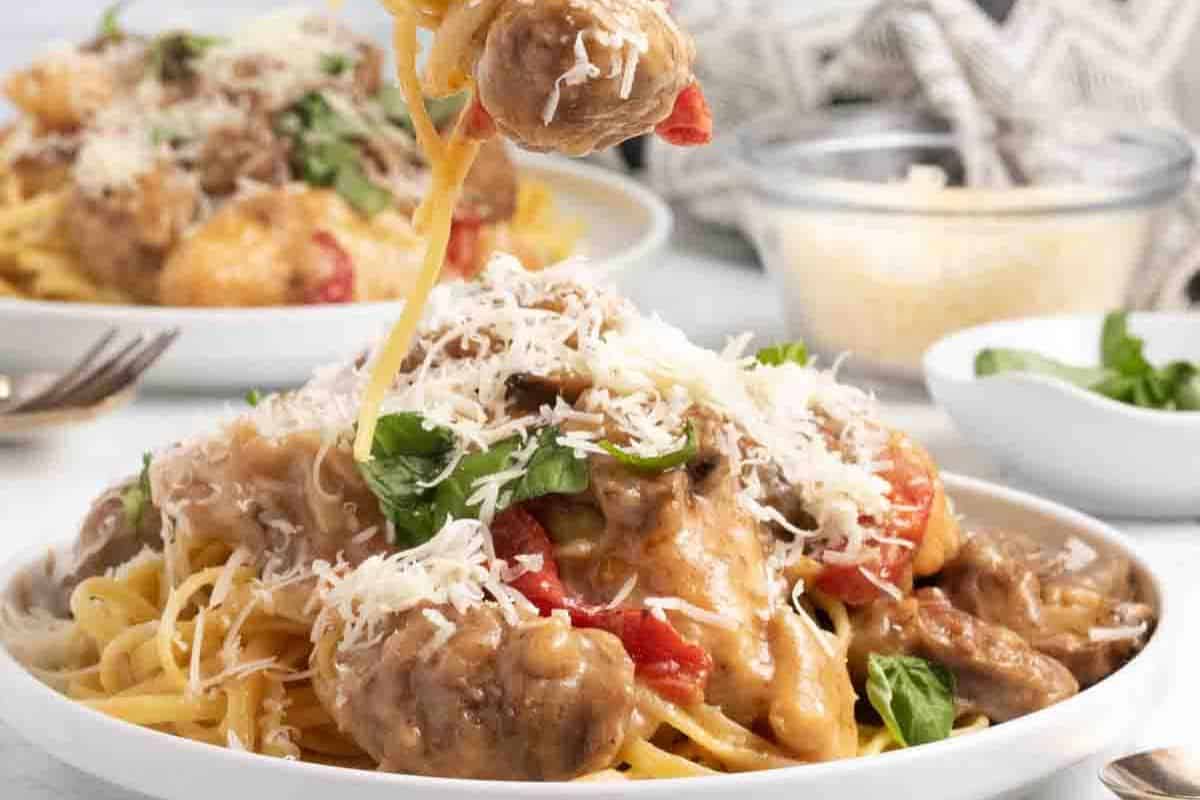 A generous serving of spaghetti is topped with tender chicken and savory sausage in a creamy, flavorful Tuscan-style sauce. Fresh basil and a generous sprinkle of Parmesan cheese add a vibrant finish to this comforting, restaurant-worthy dish.