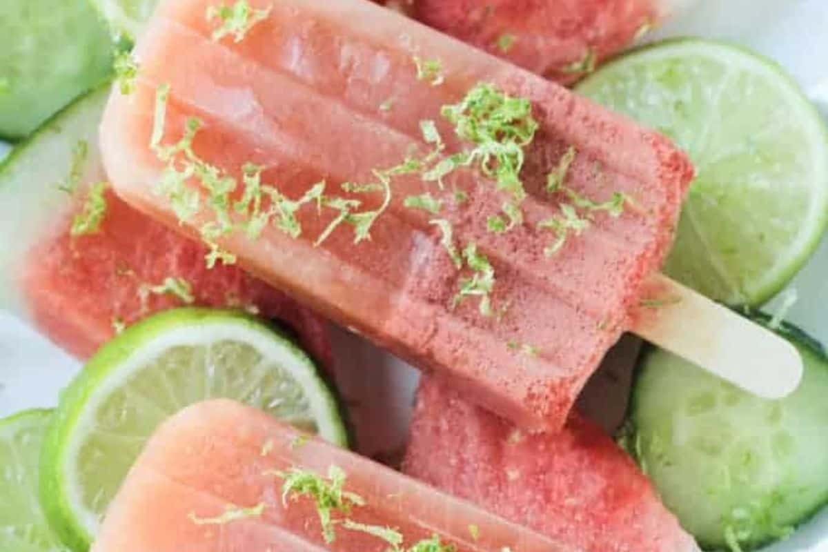 Refreshing watermelon popsicles garnished with lime zest are arranged on slices of fresh cucumber and lime—an ideal way to beat the heat and inspire your next popsicle recipes.