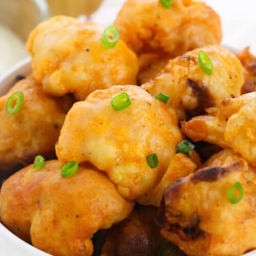 A bowl of golden-brown Air Fryer Cauliflower Wings, garnished with chopped green onions.