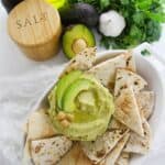 A bowl of pita chips with the dip on the side.