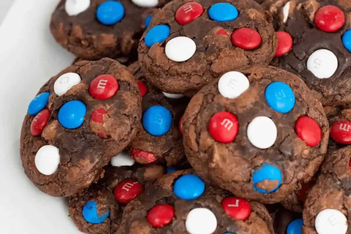 A plate of chocolate cookies topped with red, white, and blue candy-coated chocolates—perfect for Memorial Day or other patriotic party foods celebrations.