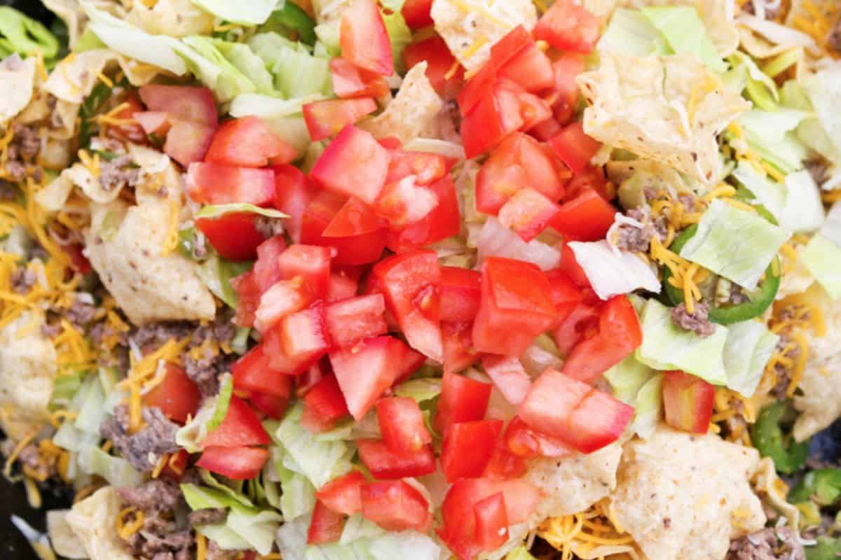 A close-up of nachos topped with chopped lettuce, diced tomatoes, ground beef, shredded cheese and tortilla chips—perfect inspiration for your next trip or to add to your list of camping recipes.